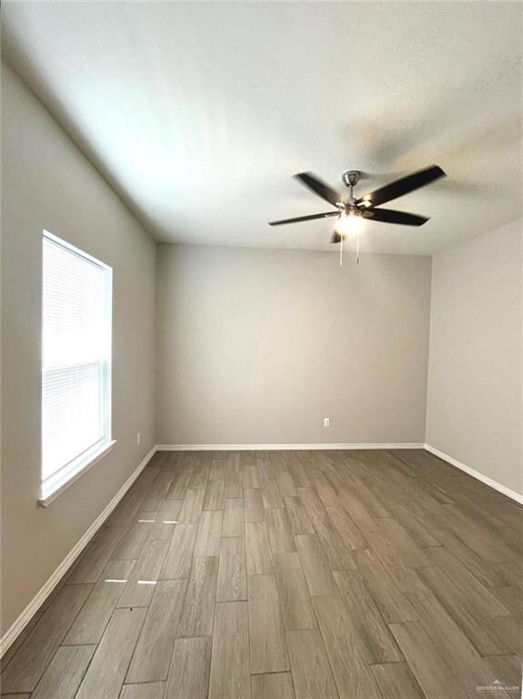 Empty room featuring light wood-style flooring, a ceiling fan, and a textured ceiling