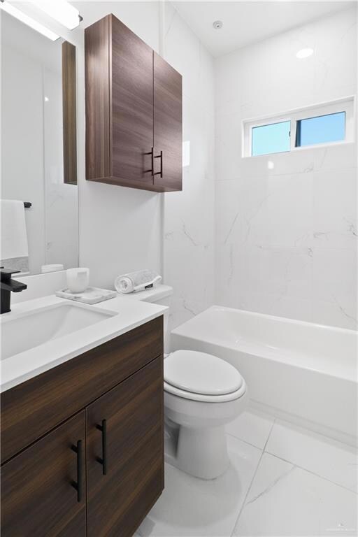 Full bathroom with vanity, tiled shower / bath, and toilet