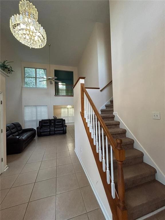 Staircase featuring a towering ceiling, a ceiling fan, tile patterned floors, and a chandelier