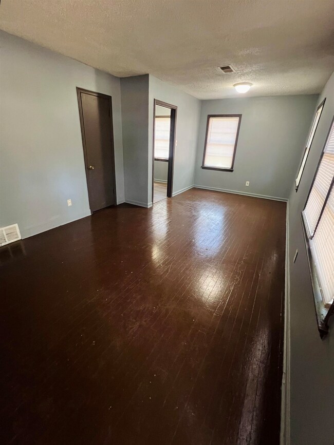 Spare room with a textured ceiling and wood-type f