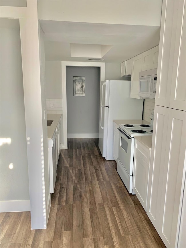 Kitchen with white cabinets, backsplash, and white appliances