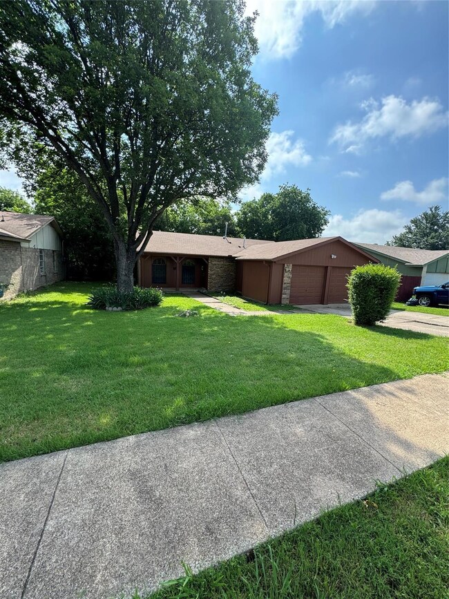 Single story home with a garage and a front lawn