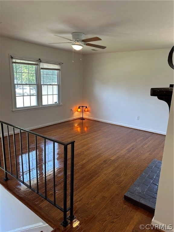 Staircase featuring ceiling fan and dark wood-type flooring