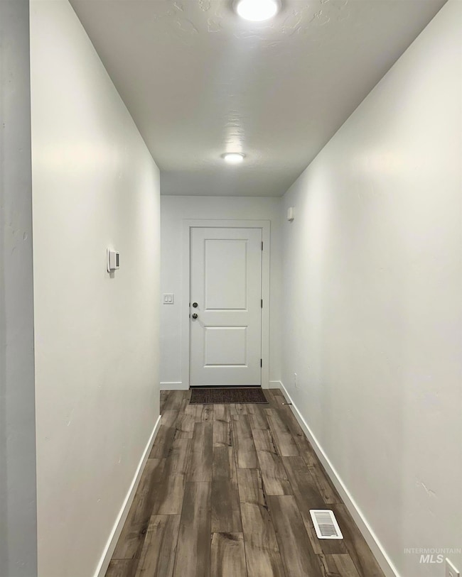 Corridor featuring baseboards and dark wood finished floors