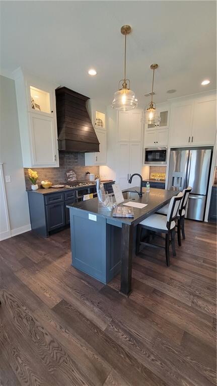 Kitchen with white cabinets, refrigerator, extractor fan, dark wood-type flooring, and blue cabinets