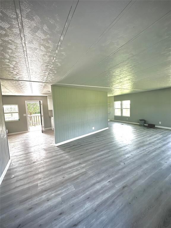 Unfurnished living room with plenty of natural light, baseboards, and wood finished floors