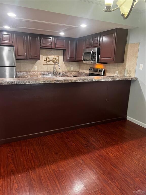 Kitchen with backsplash, dark wood finished floors, recessed lighting, fridge, and a sink