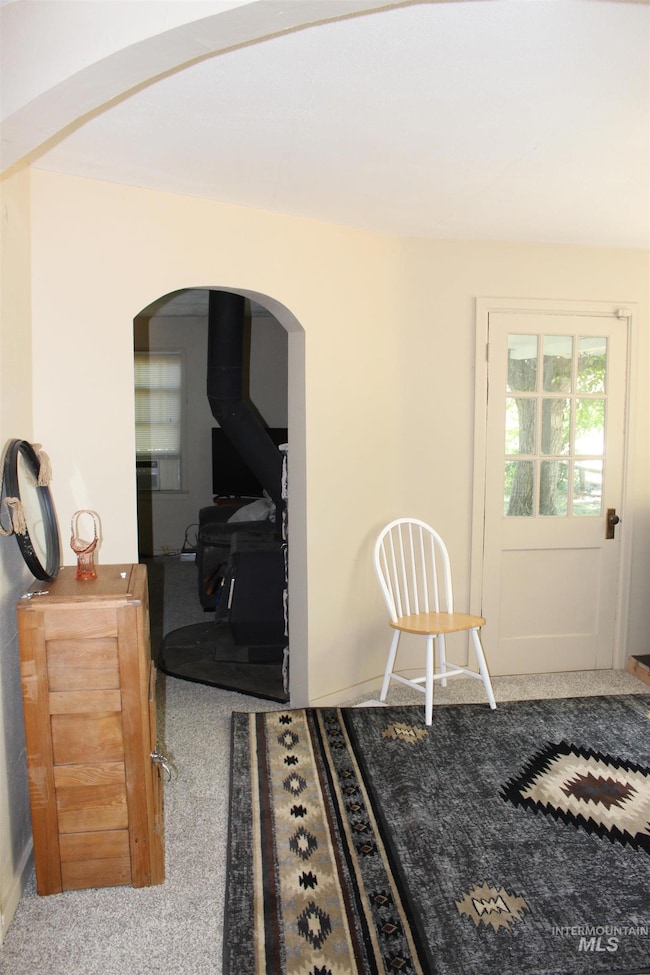 Dining space with arched walkways, carpet, and a wood stove