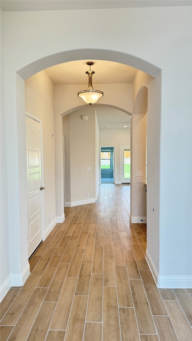 Hall featuring wood finished floors and arched walkways