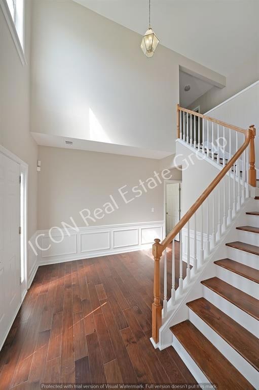 Stairs with visible vents, a high ceiling, and woo
