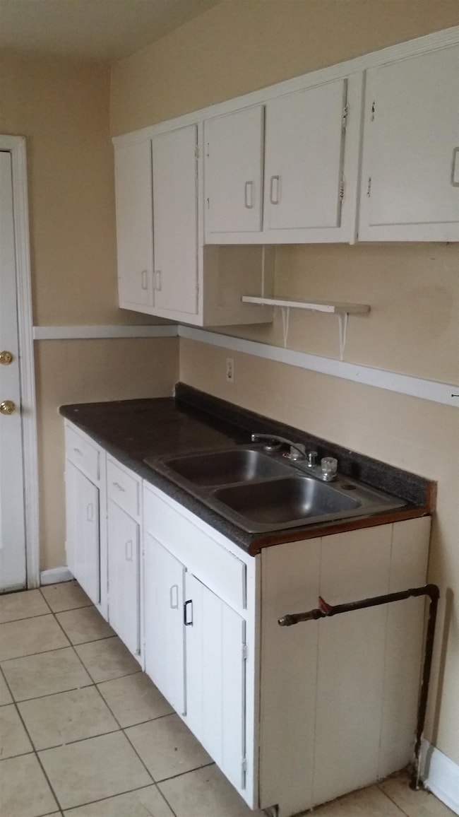 Kitchen featuring white cabinetry, light tile patterned floors, and dark countertops