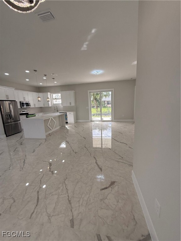 Unfurnished living room featuring light marble finish floors and recessed lighting