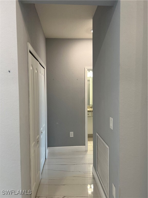Corridor featuring baseboards and visible vents