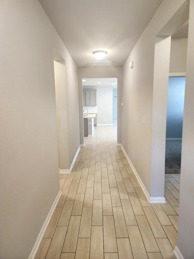 Hallway featuring light wood-style floors and bas