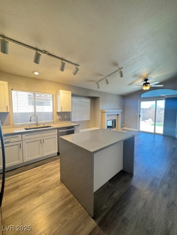 Kitchen with rail lighting, a center island, white cabinetry, a textured ceiling, and light wood-type flooring