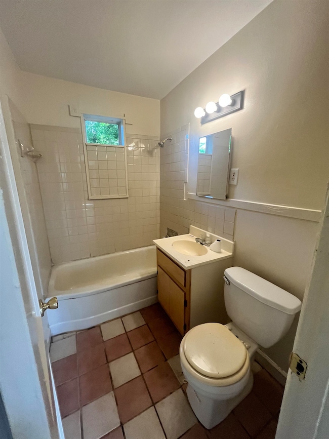 Bathroom featuring toilet, vanity, bathtub / shower combination, and tile patterned flooring