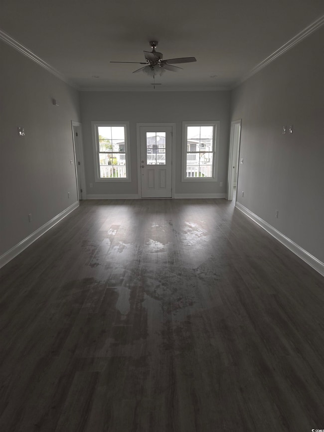 Empty room featuring ceiling fan, crown molding, and baseboards