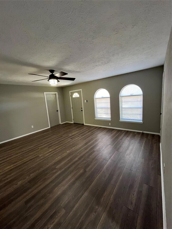 Unfurnished room featuring a textured ceiling, ceiling fan, and dark wood-type flooring