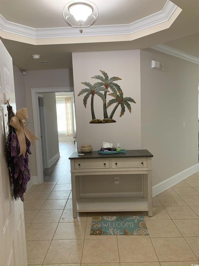 Corridor featuring crown molding and light tile patterned flooring