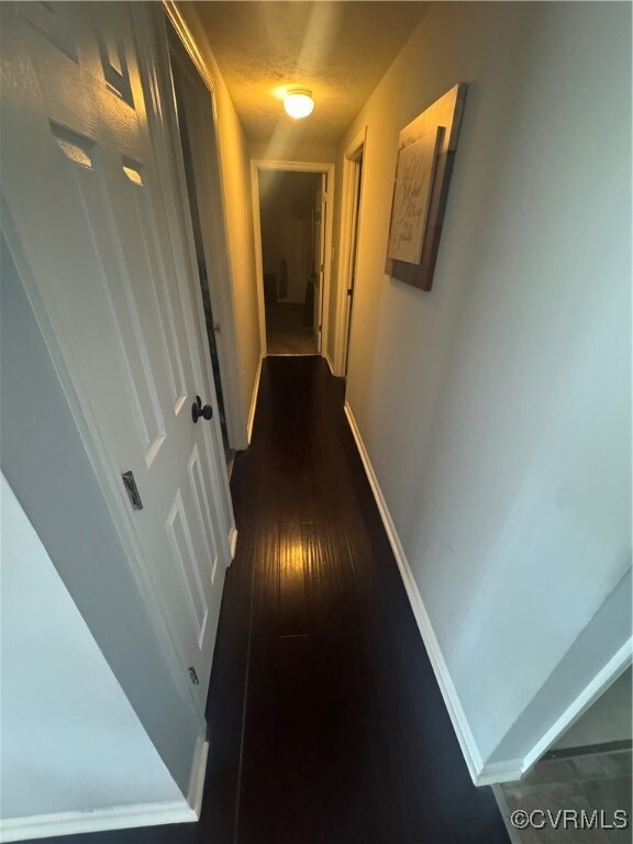 Hall featuring baseboards and dark wood finished f