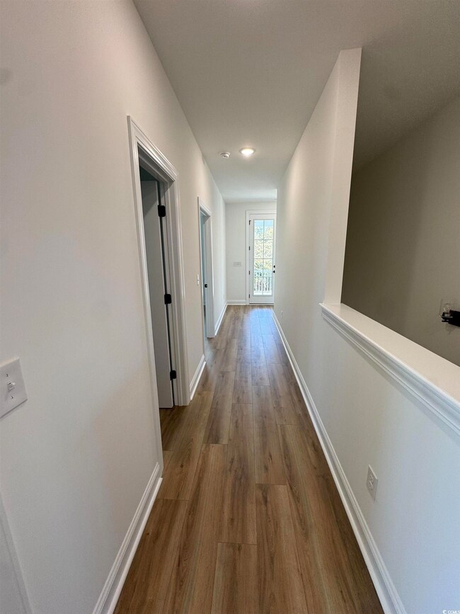 Hall featuring dark wood-style floors and baseboards