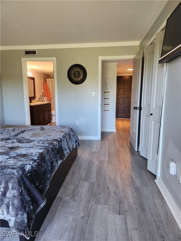Bedroom with light wood-style flooring and ensuite bath