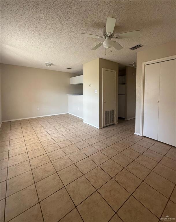 Spare room featuring ceiling fan, light tile patterned flooring, and a textured ceiling