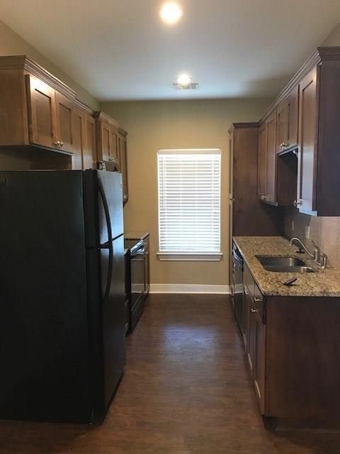 Kitchen with freestanding refrigerator, light stone countertops, range with electric cooktop, and dark wood-type flooring