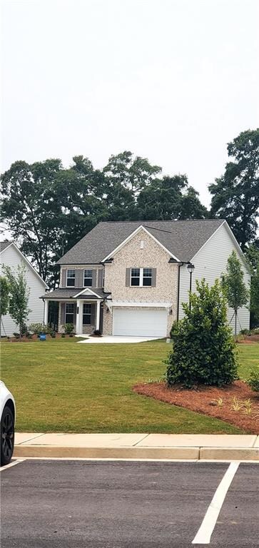 View of front of property featuring a front lawn, an attached garage, and roof with shingles