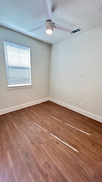 Spare room with dark wood-type flooring and baseboards