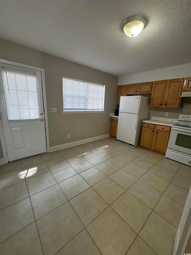 Kitchen featuring a textured ceiling, light tile p