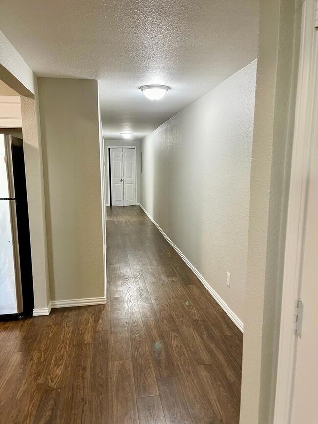 Hall featuring dark wood-style floors, a textured 