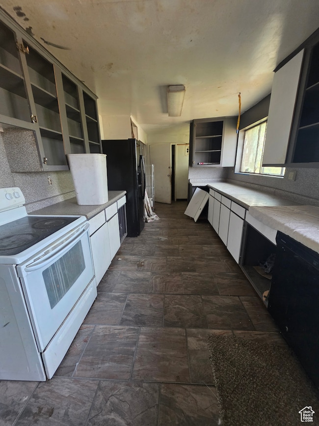 Kitchen with open shelves, black appliances, white cabinetry, light countertops, and decorative backsplash