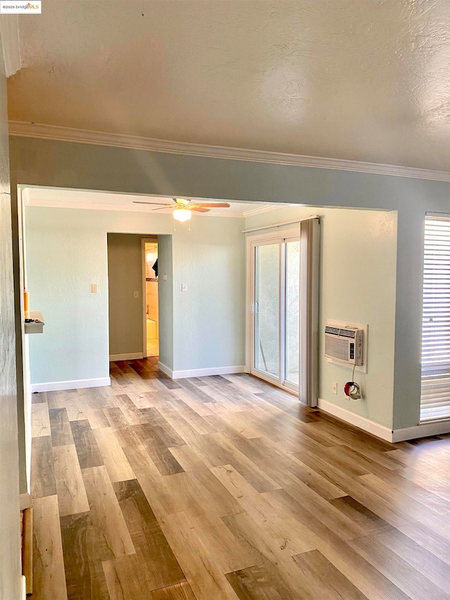 Dining Area featuring ornamental molding, baseboards, laminate wood floors, a wall unit AC, and a ceiling fan