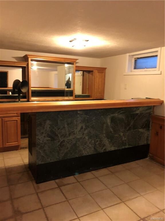 basement with detailed tile floor & custom bar are