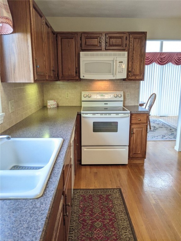 Applianced eat-in kitchen with hardwood floors.