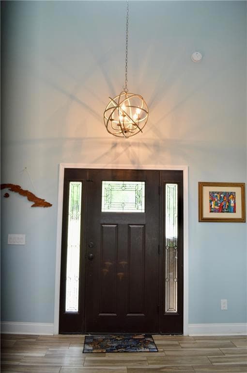 Foyer with baseboards, a chandelier, and plenty of
