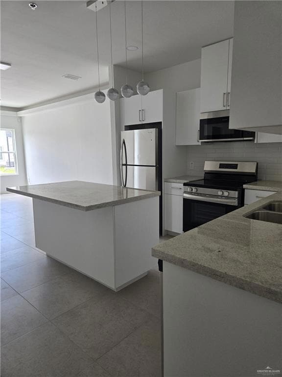 Kitchen with appliances with stainless steel finishes, backsplash, a center island, white cabinets, and hanging light fixtures