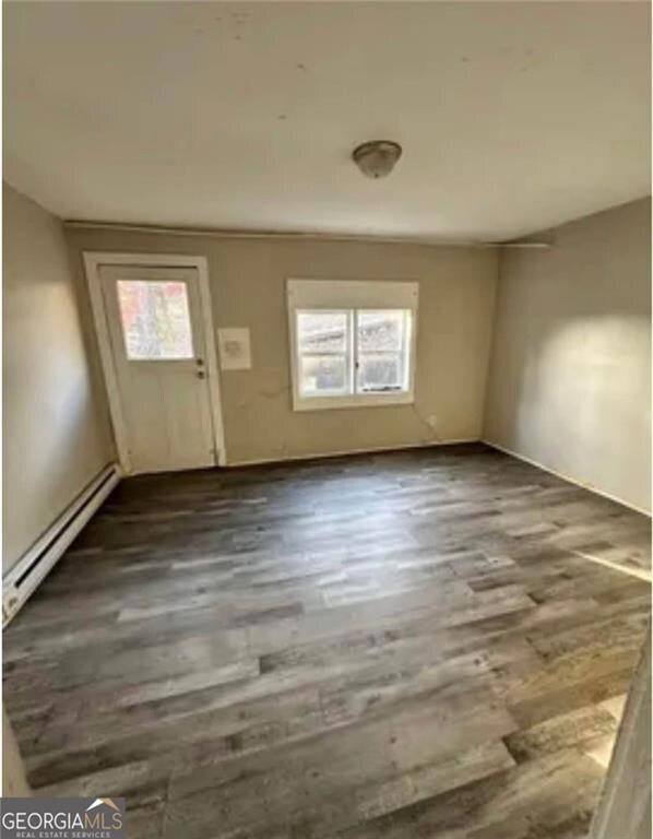 Foyer entrance with a baseboard radiator, plenty of natural light, wood finished floors, and baseboards