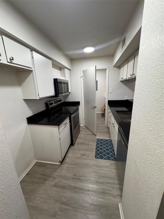 Kitchen featuring white cabinets, wood finished fl