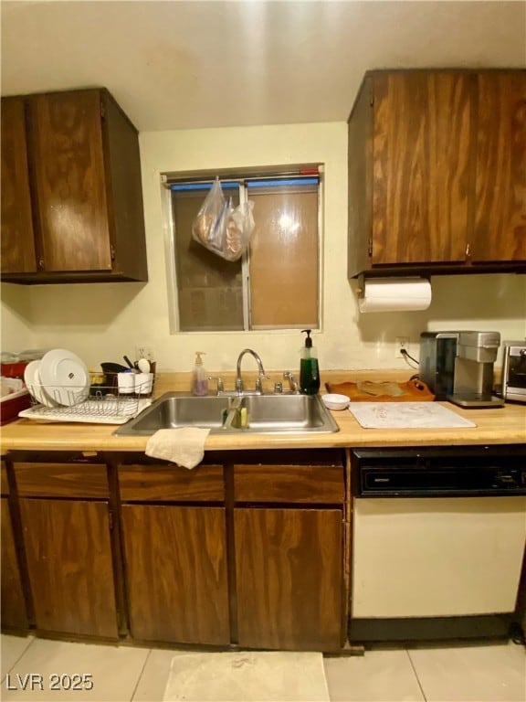 Kitchen with white dishwasher, a sink, light tile