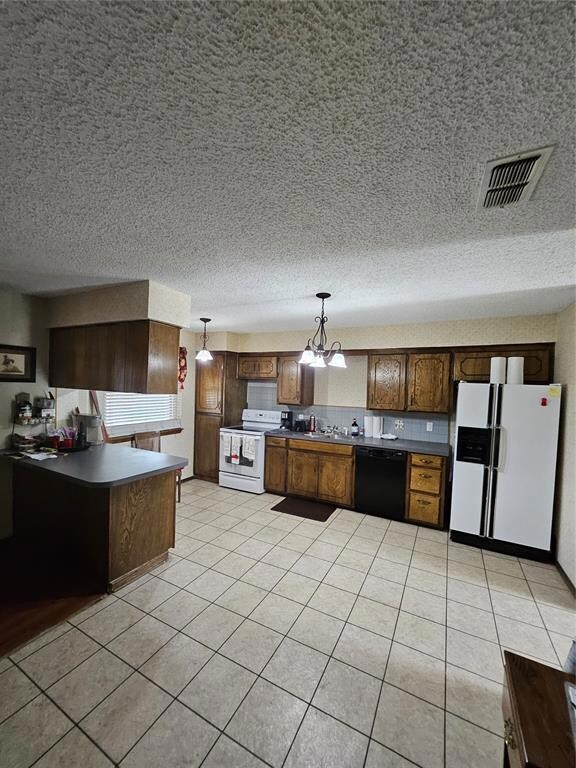 Kitchen with fridge, stove, visible vents, hanging