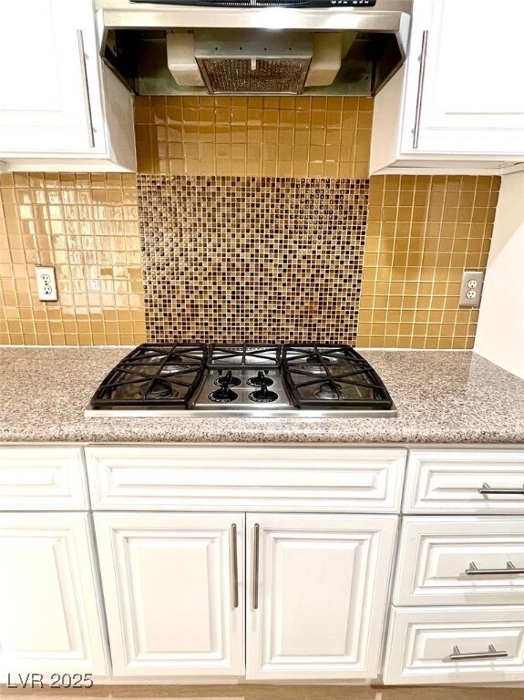 Kitchen with exhaust hood, white cabinetry, stainl