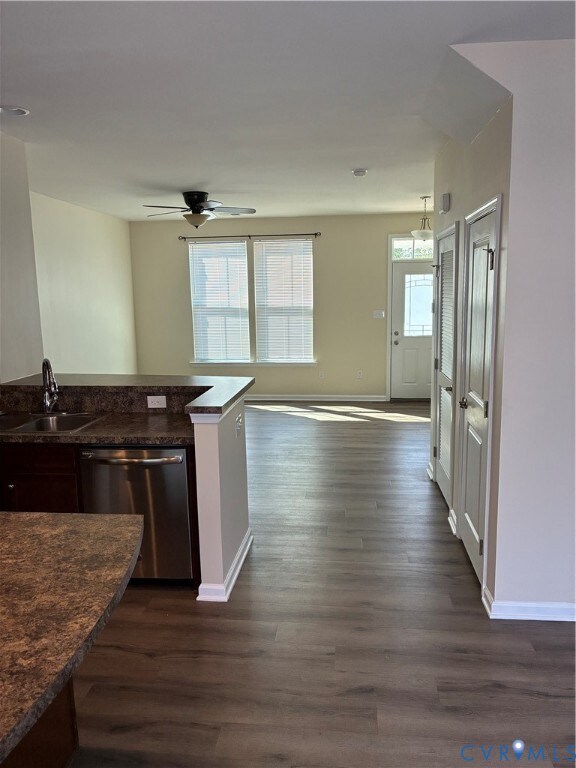 Kitchen with open floor plan, dishwasher, dark wood-style floors, dark stone counters, and a ceiling fan