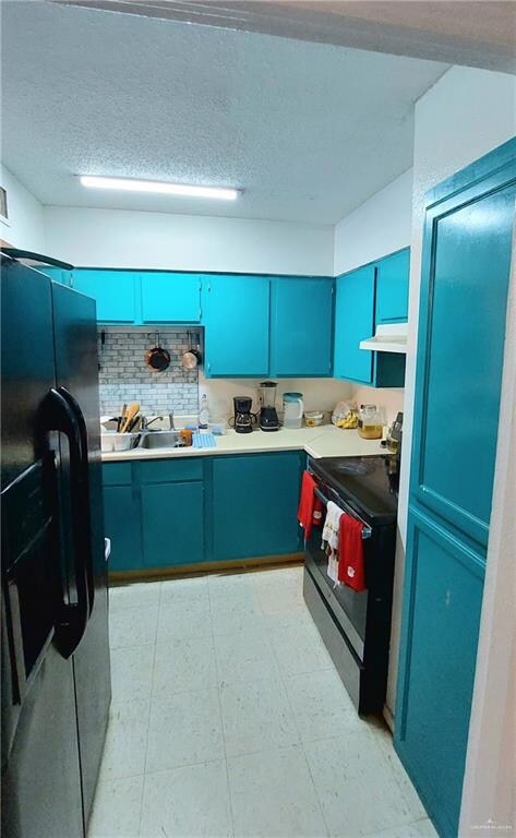 Kitchen with blue cabinets, light countertops, black appliances, decorative backsplash, and a textured ceiling