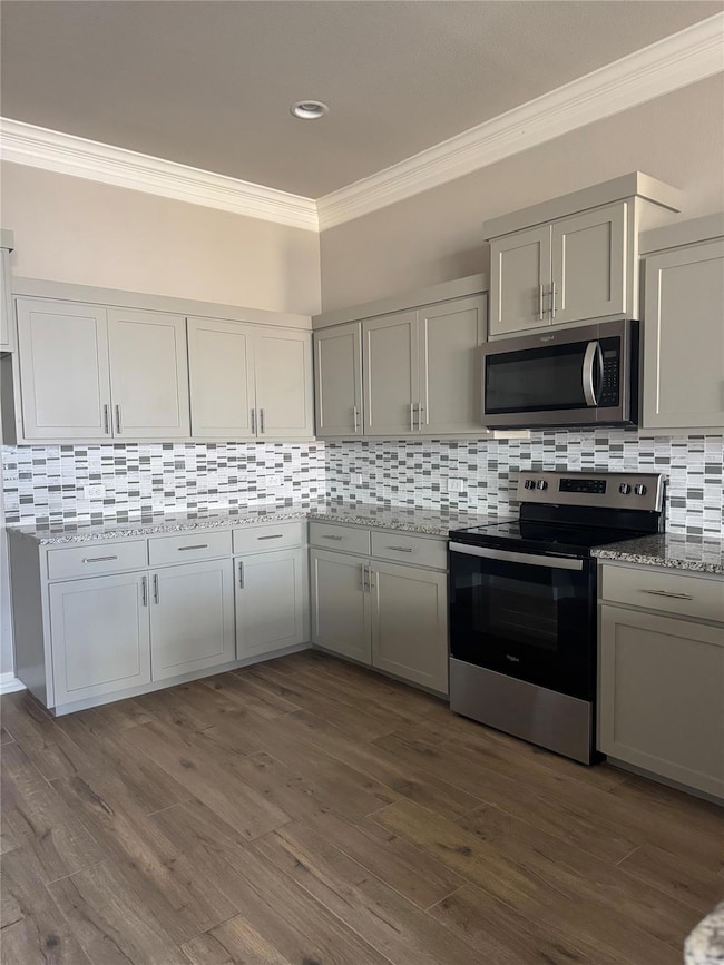 Kitchen with tasteful backsplash, stainless steel appliances, ornamental molding, and gray cabinetry