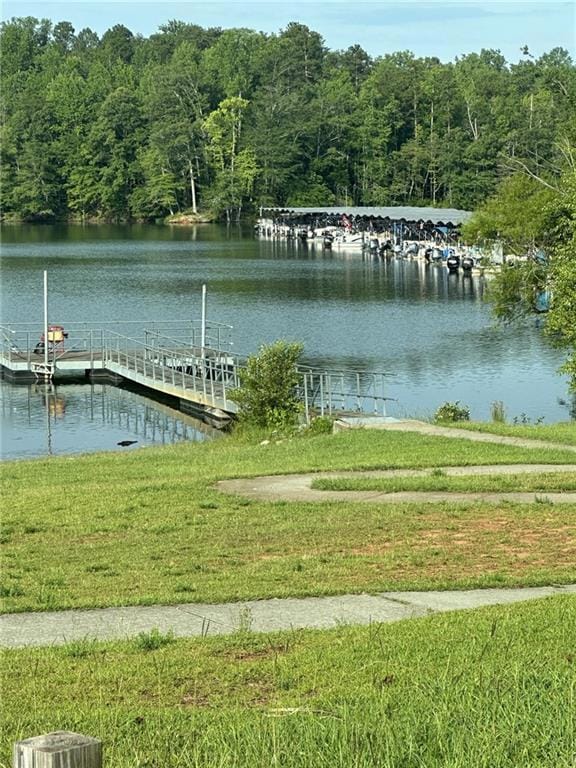 Dock area with a water view, a yard, and a wooded view