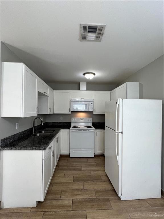 Kitchen with fridge, stove, wood finish floors, and white cabinets