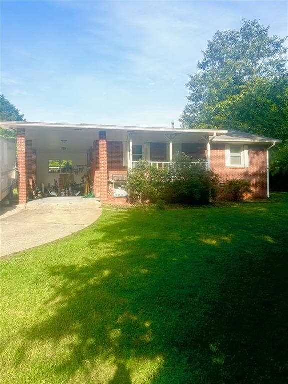 Rear view of house featuring driveway, a lawn, bri