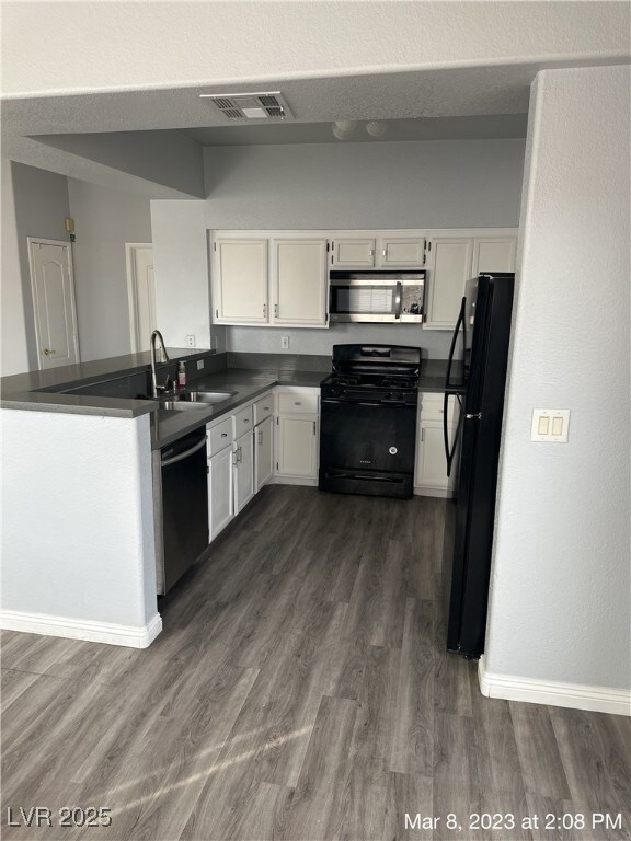 Kitchen with black appliances, dark countertops, a